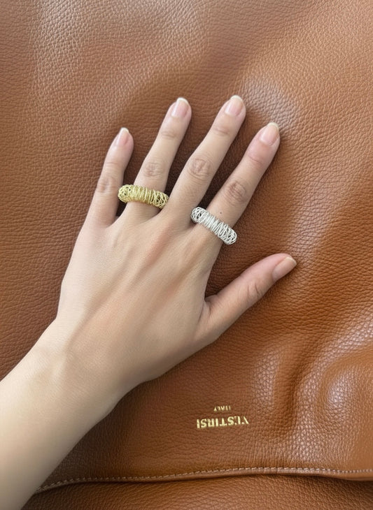 Hand wearing two rings on a brown leather surface with 'VESTIRSI' branding.