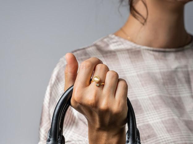 18k gold ring with white opal being worn on middle finger 